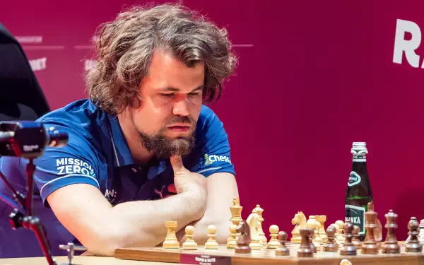 Magnus Carlsen, the renowned chess champion, deep in thought during a match, with chess pieces in front of him. This high-definition image serves as a captivating sports-themed wallpaper.