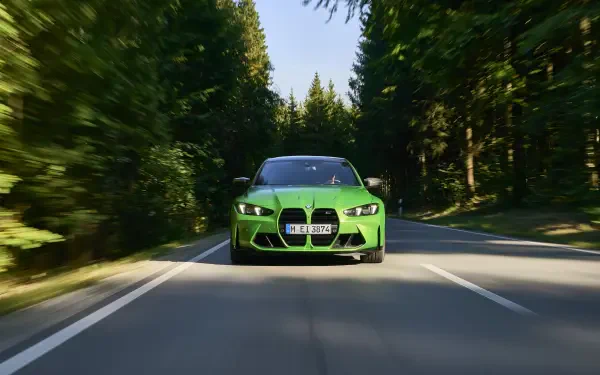 A vibrant green BMW M3 drives down a winding road, surrounded by lush trees, in this stunning 4K Ultra HD PC desktop wallpaper and background.