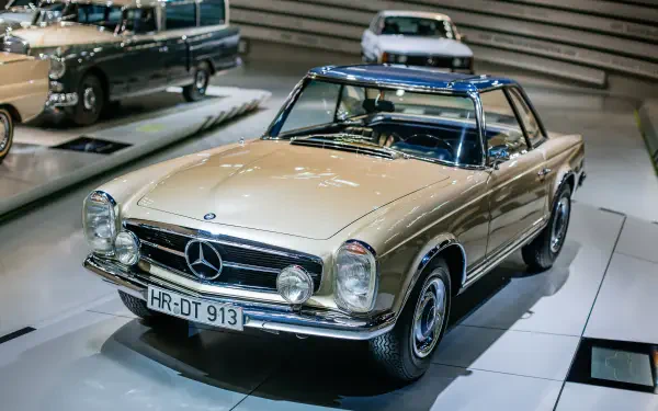 A classic Mercedes-Benz 230 SL showcased in a sleek, modern setting, featuring a striking gold exterior and a blue roof, captured in 4K Ultra HD.