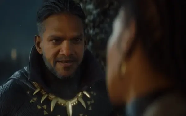 A dramatic scene from the video game MARVEL 1943: Rise of Hydra, featuring a character in a dark cloak adorned with an iconic necklace, set against an atmospheric background.