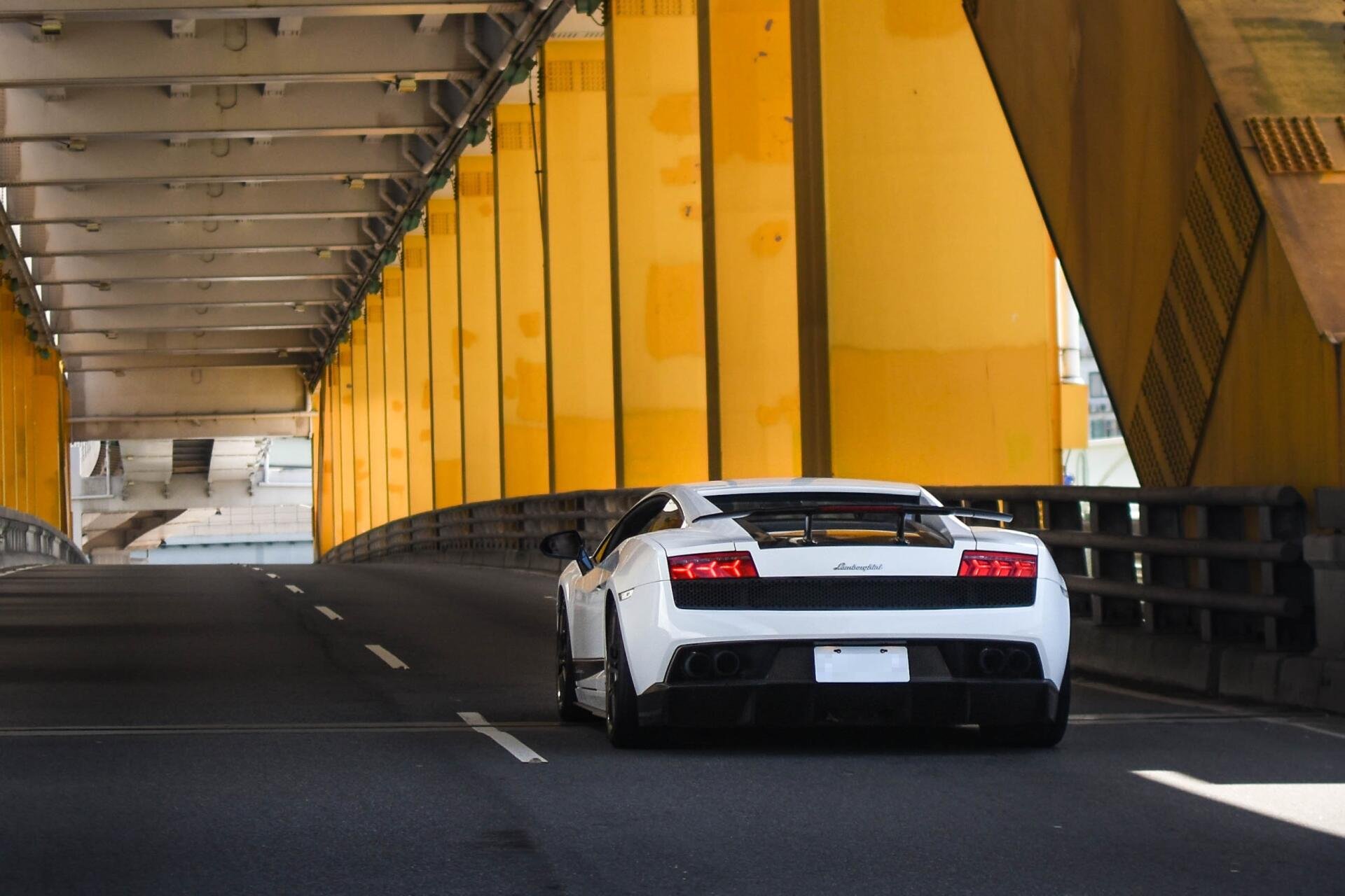 Rear view of a white Lamborghini Gallardo driving through a yellow-toned tunnel — 2K Quad HD PC desktop wallpaper and background.