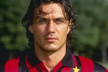 A close-up portrait of Paolo Maldini wearing an A.C. Milan jersey, showcasing his intense gaze and defining features, set against a vibrant outdoor background.