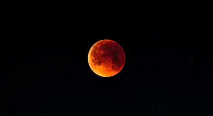 A stunning 4K Ultra HD wallpaper featuring a lunar eclipse, with the moon glowing in deep orange against a starry night sky.