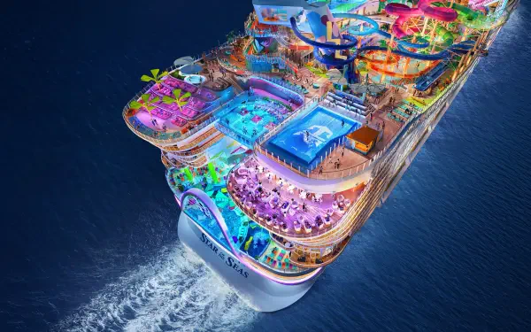 A vibrant aerial view of a Royal Caribbean cruise ship, showcasing its colorful decks, pools, and entertainment areas, against a deep blue ocean backdrop. Ideal for desktop wallpaper.