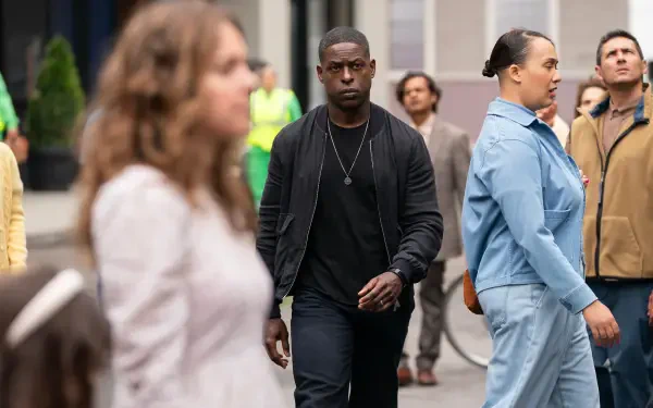 A scene from the TV show Paradise (2025) featuring Sterling K. Brown walking through a bustling crowd, showcasing a vibrant urban backdrop in HD.