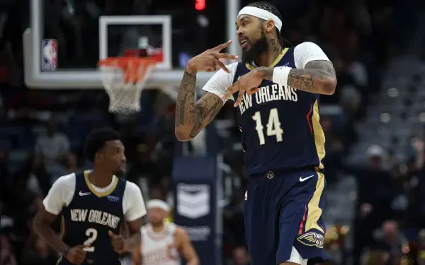 Brandon Ingram celebrates a play on the court, wearing the New Orleans Pelicans jersey, with teammates in the background during an NBA game. A dynamic sports wallpaper for fans.