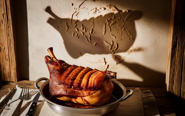A mouthwatering roasted pork dish sits in a silver pan, casting a shadow against a textured background, designed as a stunning 4K Ultra HD desktop wallpaper.
