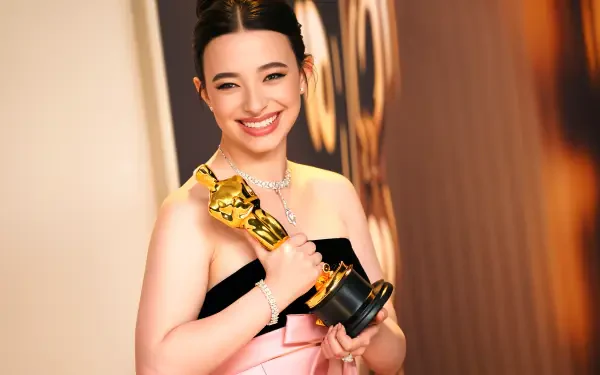Mikey Madison beams with joy at the Academy Awards, holding her Oscar in a stunning pink and black gown, captured in vibrant 4K Ultra HD.
