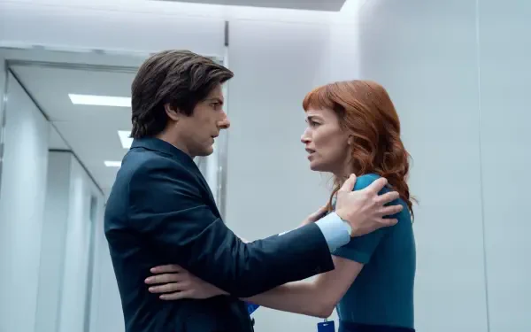 A dramatic moment from the TV show Severance featuring Adam Scott and Britt Lower. The image captures an intense exchange in a sleek, modern office environment.