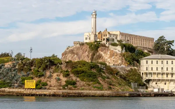 HD desktop wallpaper showcasing Alcatraz Island in California with its historic prison buildings and lighthouse against a partly cloudy sky.