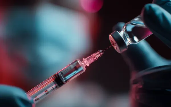 Close-up of a gloved hand drawing vaccine liquid from a vial into a syringe, captured in sharp detail as a 4K Ultra HD PC desktop wallpaper.