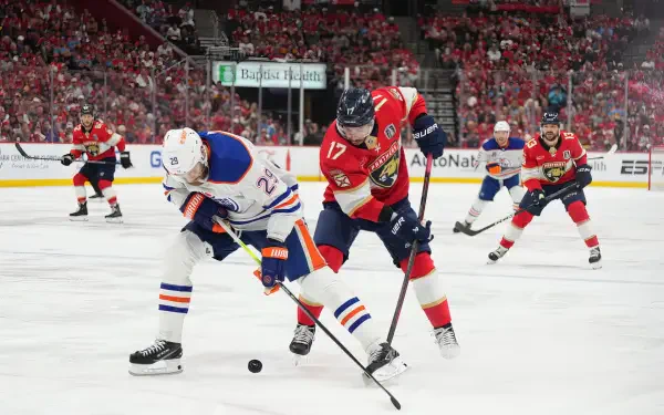 HD wallpaper showing intense NHL ice hockey action between the Edmonton Oilers and Carolina Panthers on a crowded rink during a game.