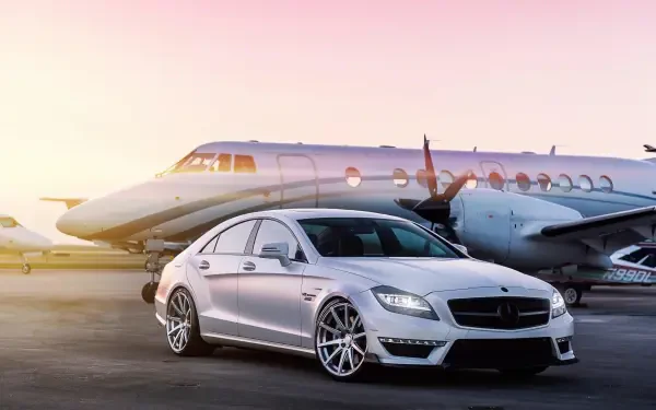 HD desktop wallpaper featuring a luxury silver Mercedes-Benz car parked in front of a private jet, symbolizing billionaire lifestyle and high-end travel.