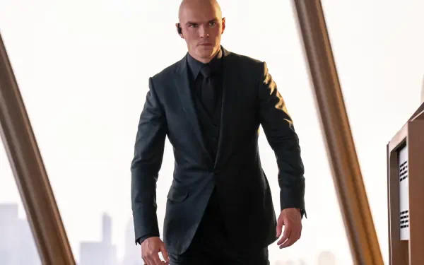 A sharply dressed man in a dark suit stands confidently indoors, captured in 8K Ultra HD as a PC desktop wallpaper for Superman (2025).