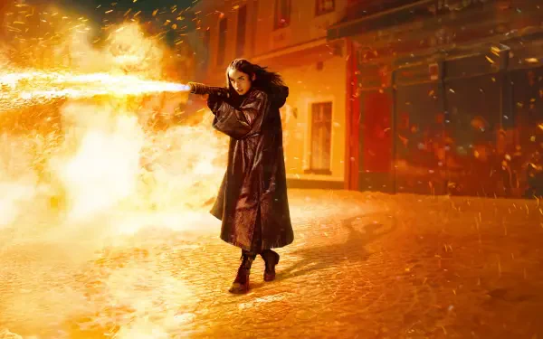 Ballerina (2025) — 8K Ultra HD PC Desktop Wallpaper: lone ballerina in a long coat releasing a fire plume on a snow-dusted, ember-lit street.