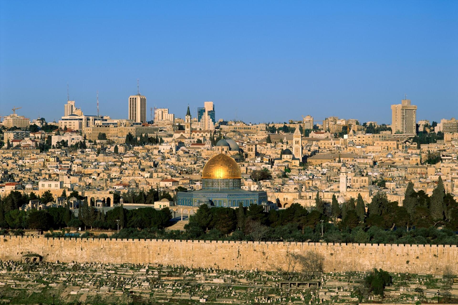 HD PC desktop wallpaper background: panoramic Jerusalem cityscape with the golden Dome of the Rock rising above stone buildings beneath a clear blue sky.
