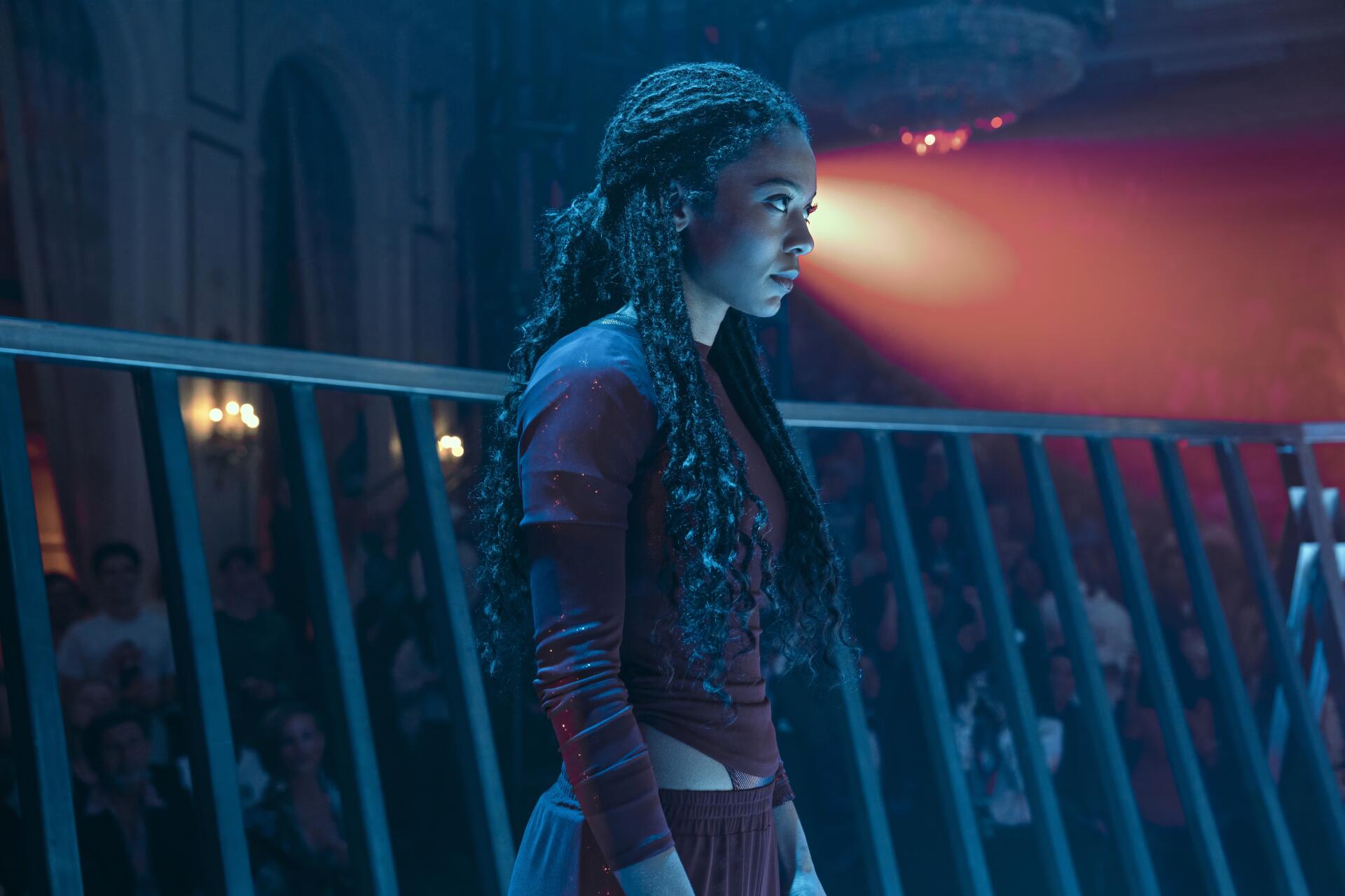 HD PC desktop wallpaper of a Gen V TV show character standing by a railing in moody blue-red light, a spotlight illuminating her focused profile.