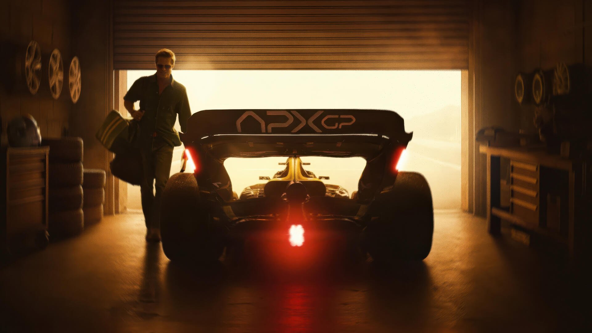 F1 (2025) 4K Ultra HD PC desktop wallpaper — rear view of an F1 car in a dim garage, red brake light glowing and a silhouetted person standing beside it as warm backlight floods the scene.