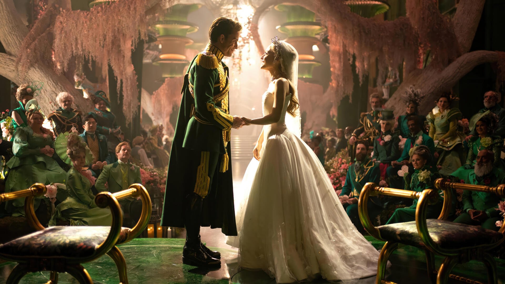 Movie 'Wicked: For Good' 4K Ultra HD PC desktop wallpaper background: two characters in wedding attire hold hands beneath a shaft of light in an ornate, crowded, candlelit hall.
