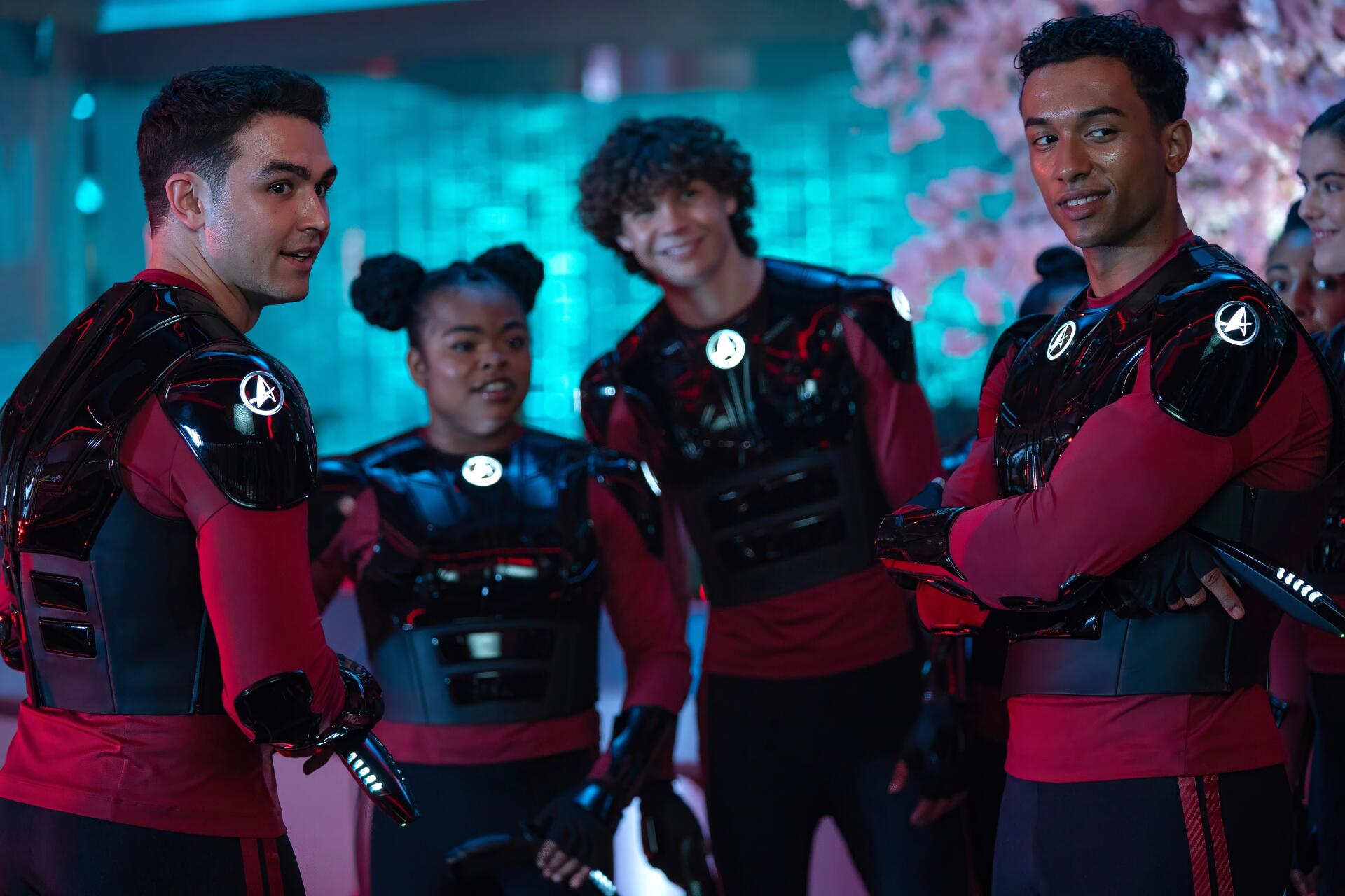 Four Starfleet Academy cadets in red-and-black uniforms smile under neon blue and pink lighting — 4K Ultra HD PC desktop wallpaper from Star Trek: Starfleet Academy.