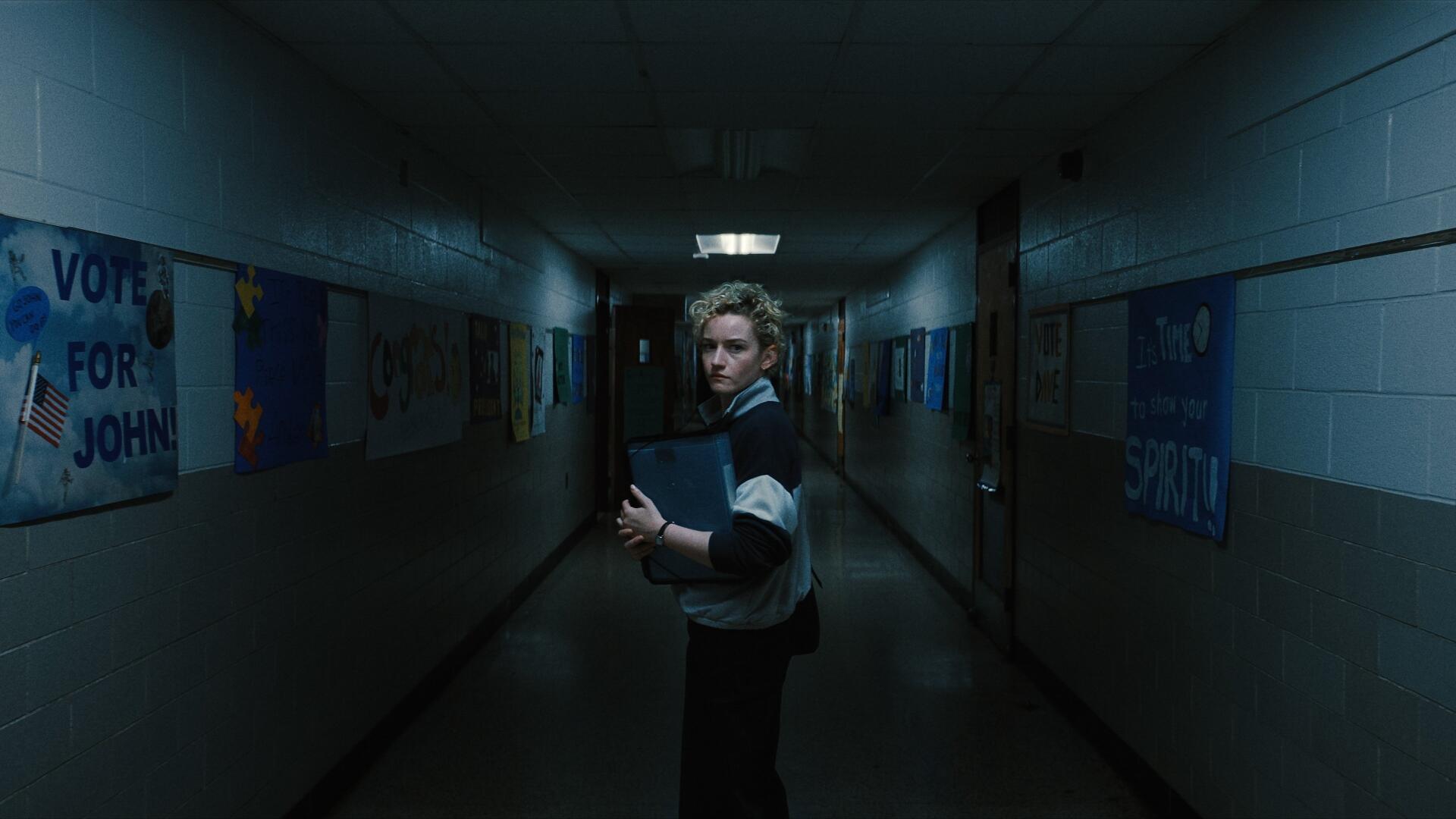 4K Ultra HD PC desktop wallpaper: lone figure in a dim school hallway clutching a weapon, moody blue-green lighting and a distant fluorescent glow.