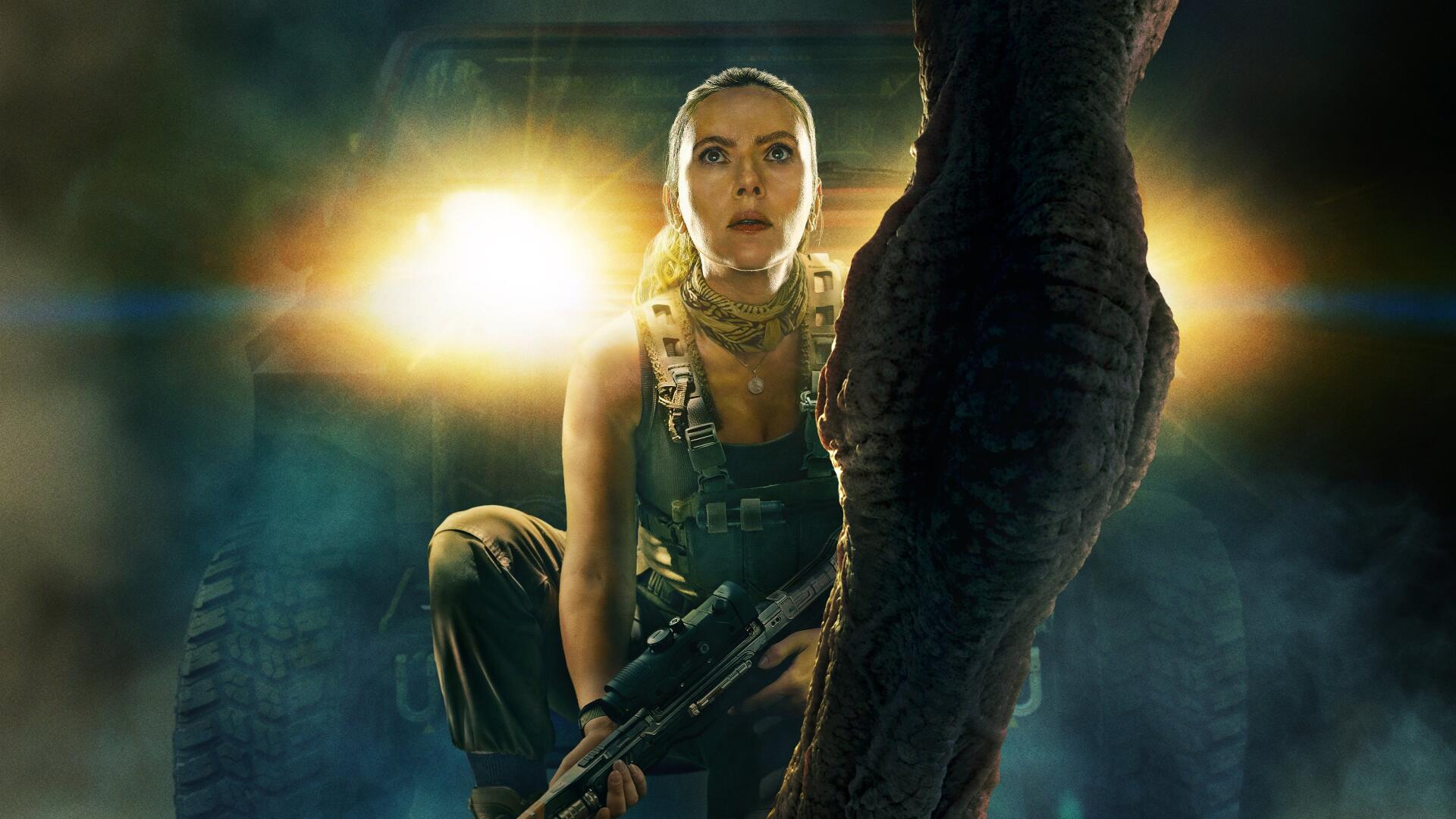Jurassic World Rebirth 4K Ultra HD PC desktop wallpaper and background: armed woman crouches with a rifle before a towering dinosaur leg, dramatic backlighting and tense cinematic atmosphere.