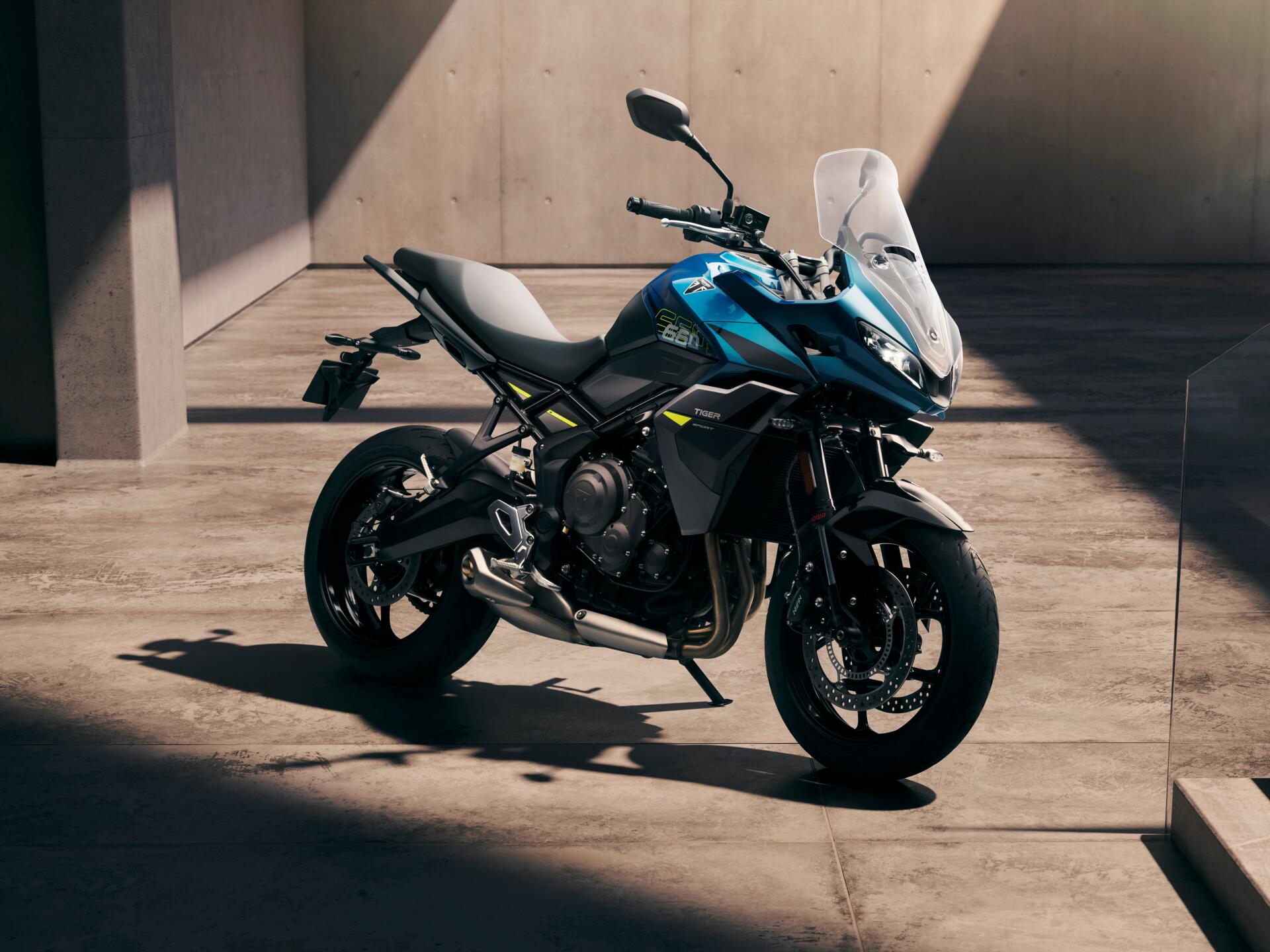 Blue Triumph Tiger Sport 660 motorcycle (vehicle) parked in a sunlit concrete courtyard, high-detail 4K Ultra HD PC desktop wallpaper background.