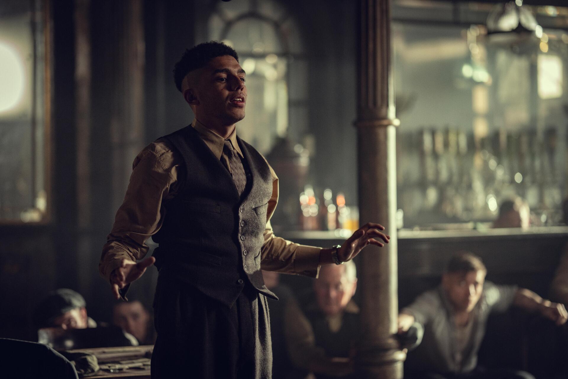 8K Ultra HD PC wallpaper: actor from Peaky Blinders: The Immortal Man in a period vest stands in a dim, smoky pub, striking a dramatic pose.