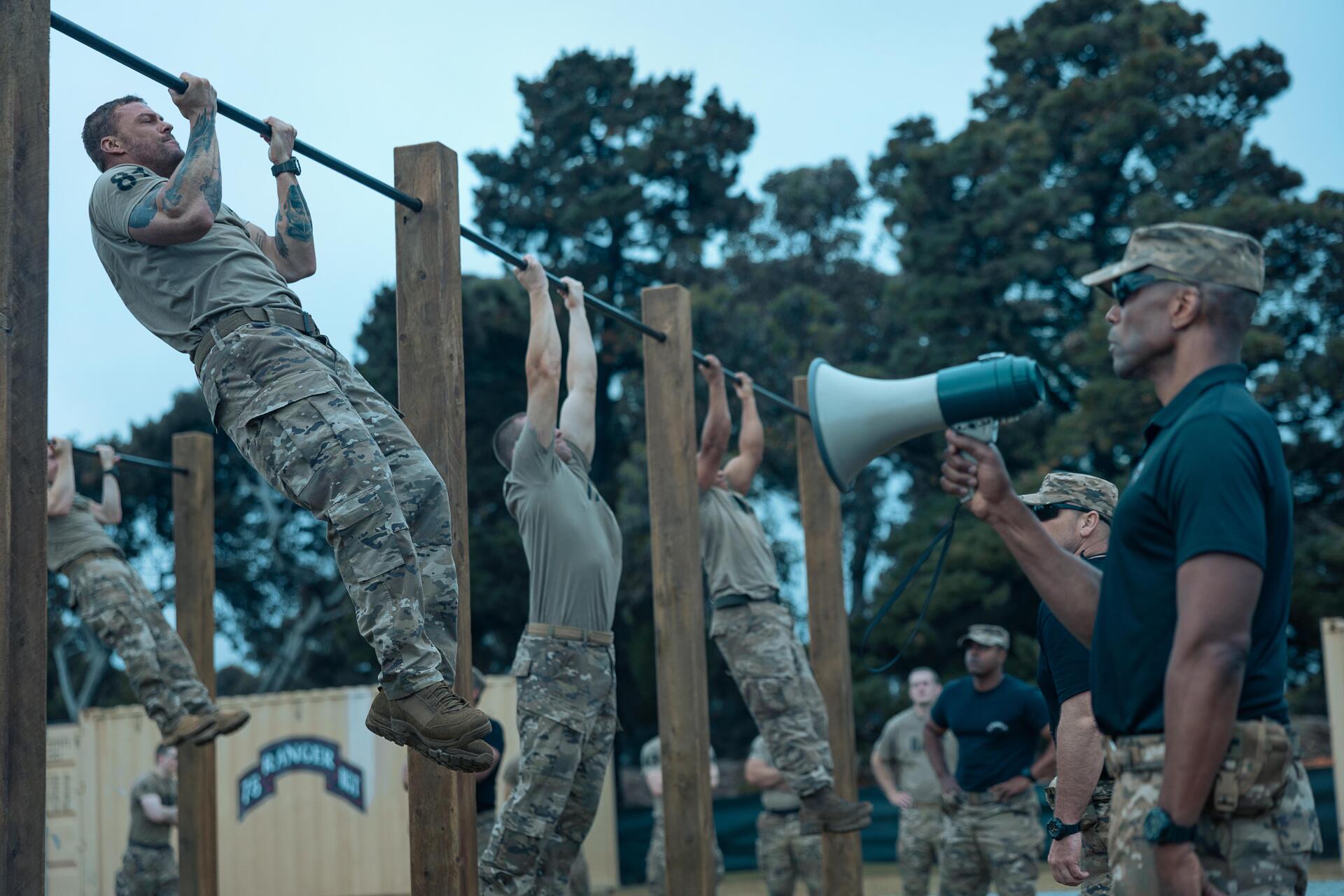 5K Ultra HD PC wallpaper from the movie War Machine (2026): army recruits doing pull-ups on wooden bars during outdoor military training while an officer directs them with a megaphone.
