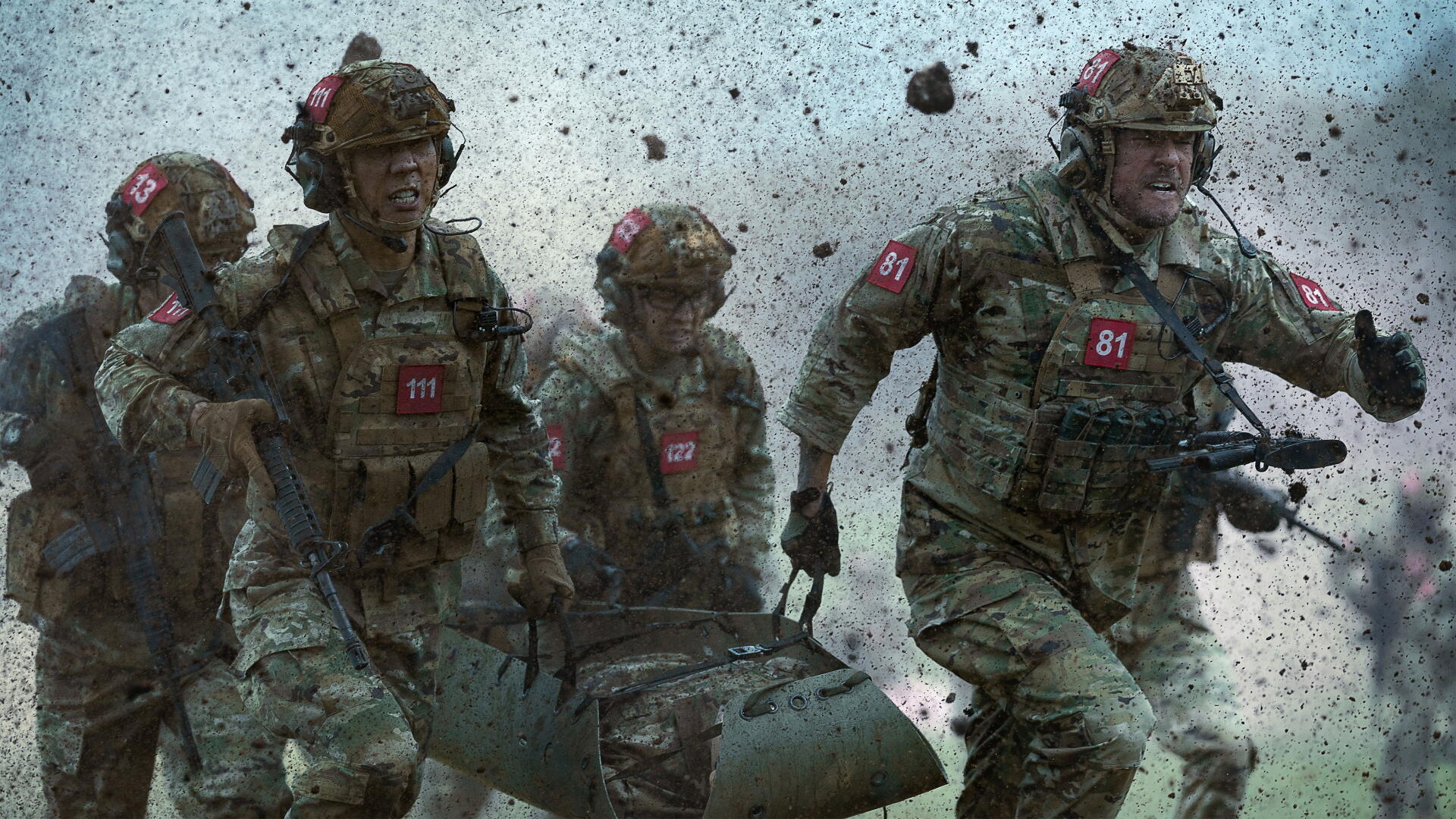 War Machine (2026) 4K Ultra HD PC desktop wallpaper: four battle-worn soldiers sprinting through debris, carrying a stretcher amid explosions and flying rubble.