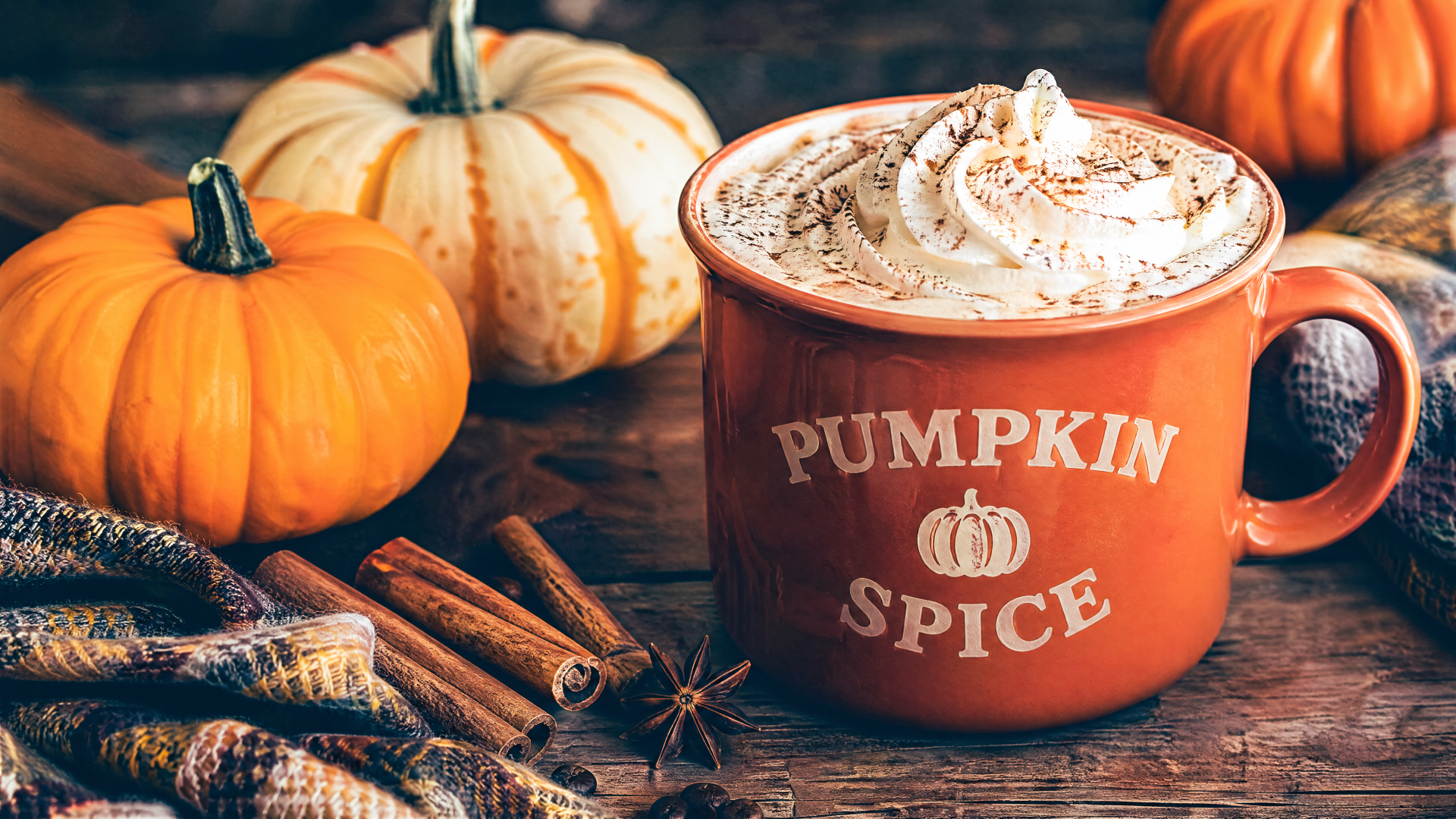 4K Ultra HD PC desktop wallpaper: pumpkin spice mug topped with whipped cream, surrounded by small pumpkins, cinnamon sticks and star anise on a rustic wooden table.