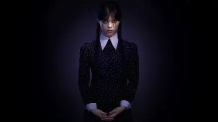 5K Ultra HD PC desktop wallpaper: Wednesday Addams in a dark dress with braided hair, pale face and clasped hands, spotlighted against a shadowy black background.