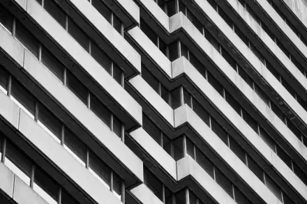 Monochrome Brutalist building facade with repeating angular balconies in strong diagonal perspective — HD PC desktop wallpaper and background.