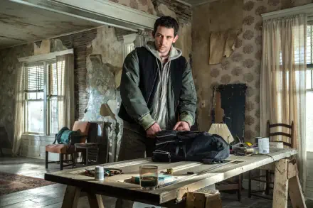 Brooding man in a dilapidated room leans over a cluttered table — cinematic still from the movie Disclosure Day, rendered as a 5K Ultra HD PC desktop wallpaper.