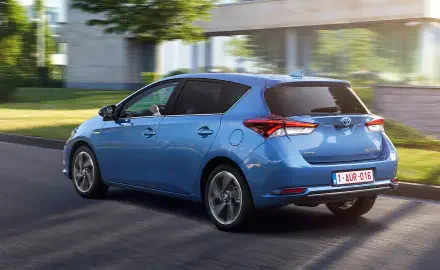 HD PC desktop wallpaper: blue Toyota Auris hatchback driving along a sunlit street, car shown from a rear three-quarter view.