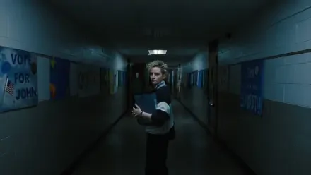 4K Ultra HD PC desktop wallpaper: lone figure in a dim school hallway clutching a weapon, moody blue-green lighting and a distant fluorescent glow.