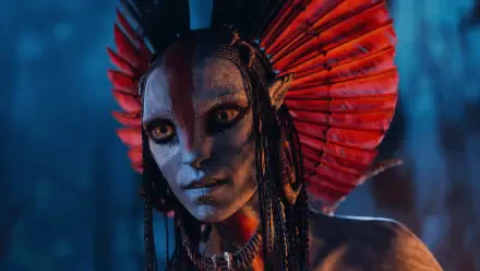 Avatar: Fire and Ash — close-up of a blue-skinned Na'vi with a red feathered headdress and glowing amber eyes, cinematic 4K Ultra HD PC desktop wallpaper/background.