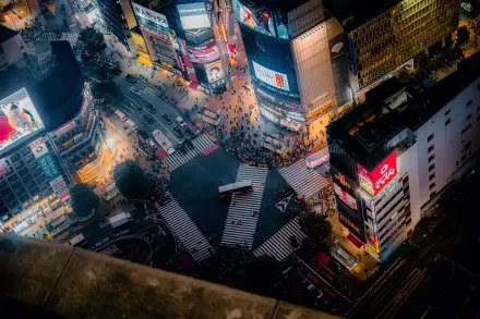 8K Ultra HD PC desktop wallpaper: aerial night cityscape of Shibuya Crossing in Tokyo, Japan — neon billboards, busy crosswalks and glowing streets.
