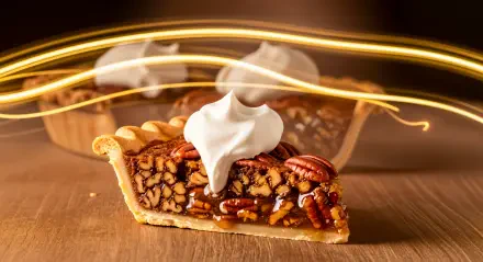 Pecan pie slice topped with whipped cream on a wooden table, warm light trails in the background — 4K Ultra HD PC desktop wallpaper/background.