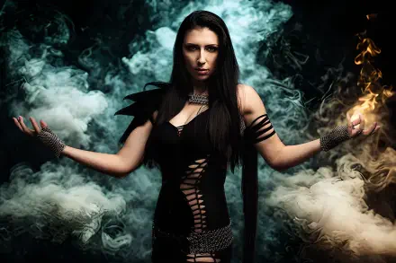 4K Ultra HD death metal desktop wallpaper: goth queen in black lace and armor, smoke and flames swirling as she raises fiery hands, dramatic pose evoking Unleash The Archers' theatrical metal vibe.