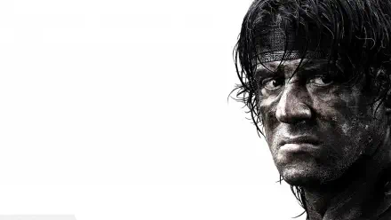 Close-up of a gritty, dirt-streaked Rambo from Rambo 4, intense stare and headband on a white background — HD PC desktop wallpaper.