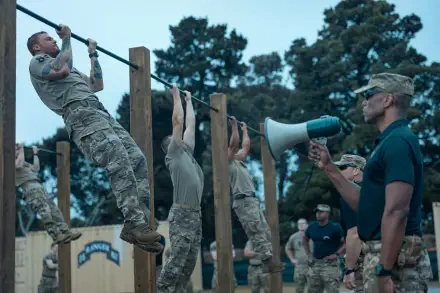 5K Ultra HD PC wallpaper from the movie War Machine (2026): army recruits doing pull-ups on wooden bars during outdoor military training while an officer directs them with a megaphone.