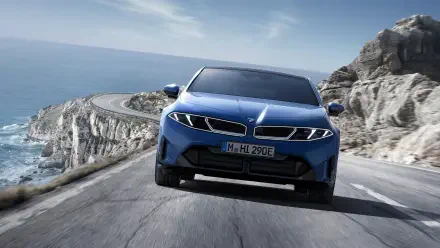 Blue BMW i3 electric vehicle front view driving on a coastal road, rendered as 4K Ultra HD PC desktop wallpaper background.