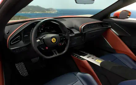 2K Quad HD desktop wallpaper of a Ferrari Amalfi Spider car interior: black leather steering wheel with prancing horse emblem, red-accented dash, blue seats and ocean view through windshield.