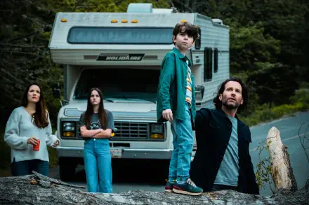 TV show From (2022) 5K Ultra HD PC desktop wallpaper: tense family of four — two adults and two youths — stand before a parked RV on a forest road under an overcast sky, wary expressions.