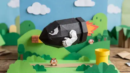Papercraft Bullet Bill soaring over a colorful Mario-style papercraft landscape — 5K Ultra HD PC desktop wallpaper and background.
