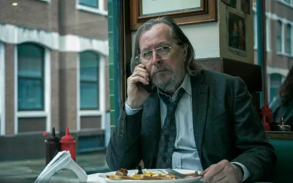 8K Ultra HD PC wallpaper: brooding, rumpled suit-wearing character from the TV show Slow Horses sits in a diner, eating and staring toward the camera.