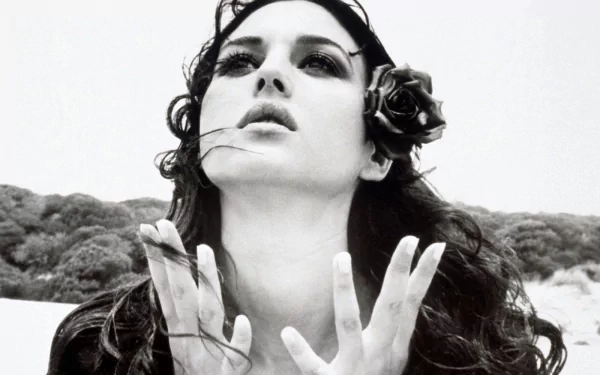 Monica Bellucci poses elegantly in this striking black-and-white image, featuring her with a rose in her hair. A captivating HD wallpaper and background for any desktop.