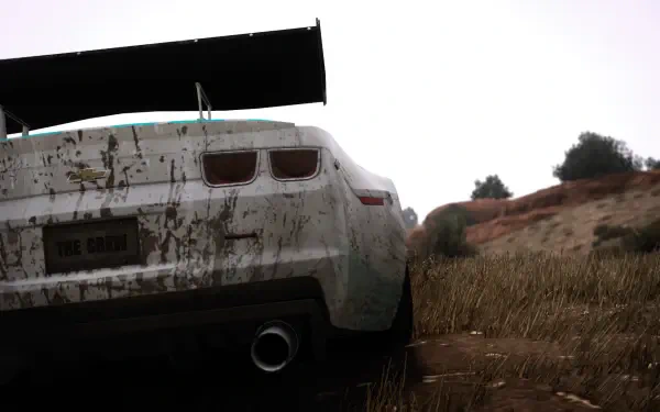 Rear view of a dirt‑splattered white Chevrolet Camaro ZL1 on a sunlit dirt track from The Crew — bright daytime HD PC desktop wallpaper/background.