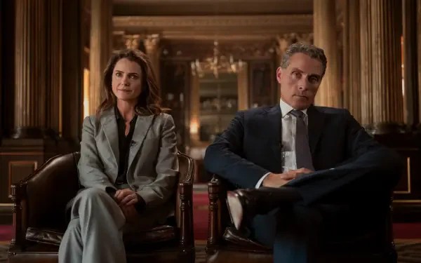 2K Quad HD desktop wallpaper: two figures from a political TV drama sit in leather chairs in an ornate government interior, formal attire, serious expressions, warm cinematic lighting.